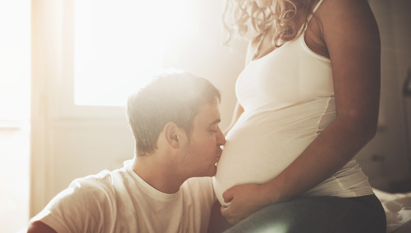 man kisses pregnant partner's belly