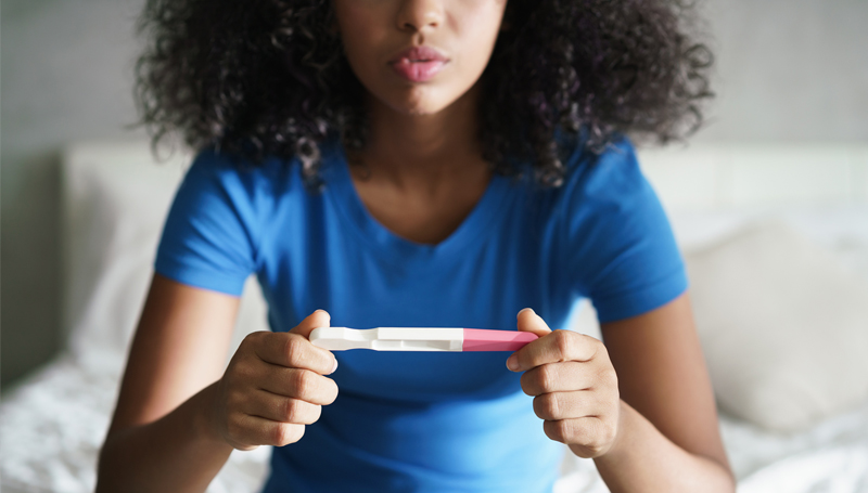 young woman looking at pregnancy test result