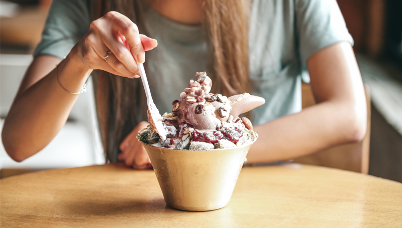 woman eating a bowl of ice cream with odd toppings