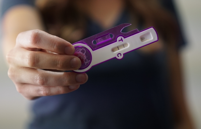 Photo of a woman holding a pregnancy test.