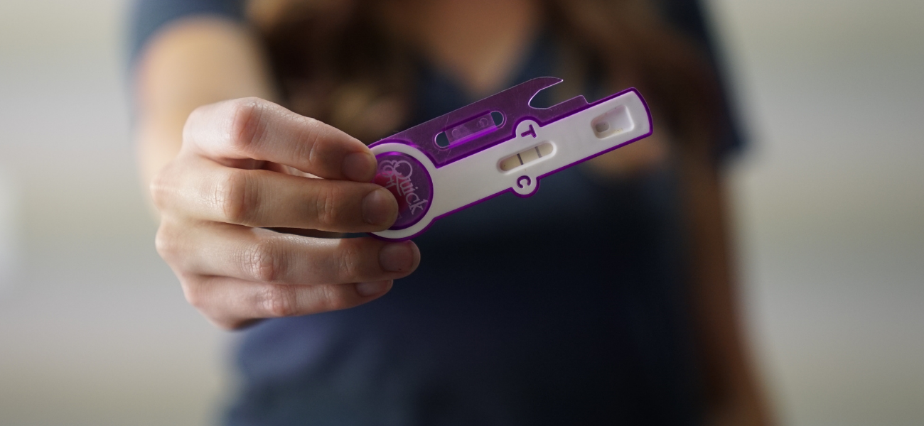 Photo of a woman holding a pregnancy test.