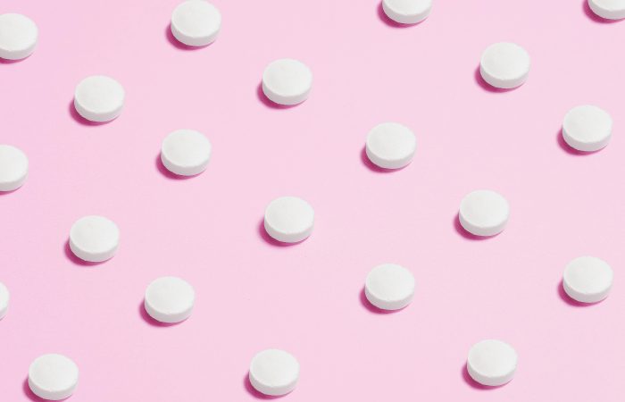 round white pills on a pink backdrop